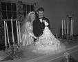 Photograph: [Bride and Groom Standing at Their Wedding Cake]