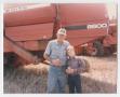 Photograph: [Photograph of Max Daniel in Front of Farm Equipment]