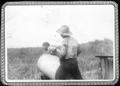 Thumbnail image of item number 1 in: '[Two men lifting a steel drum in a field at the George Ranch]'.