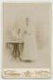 Photograph: [Portrait of a Woman in a White Gown Next to a Table]